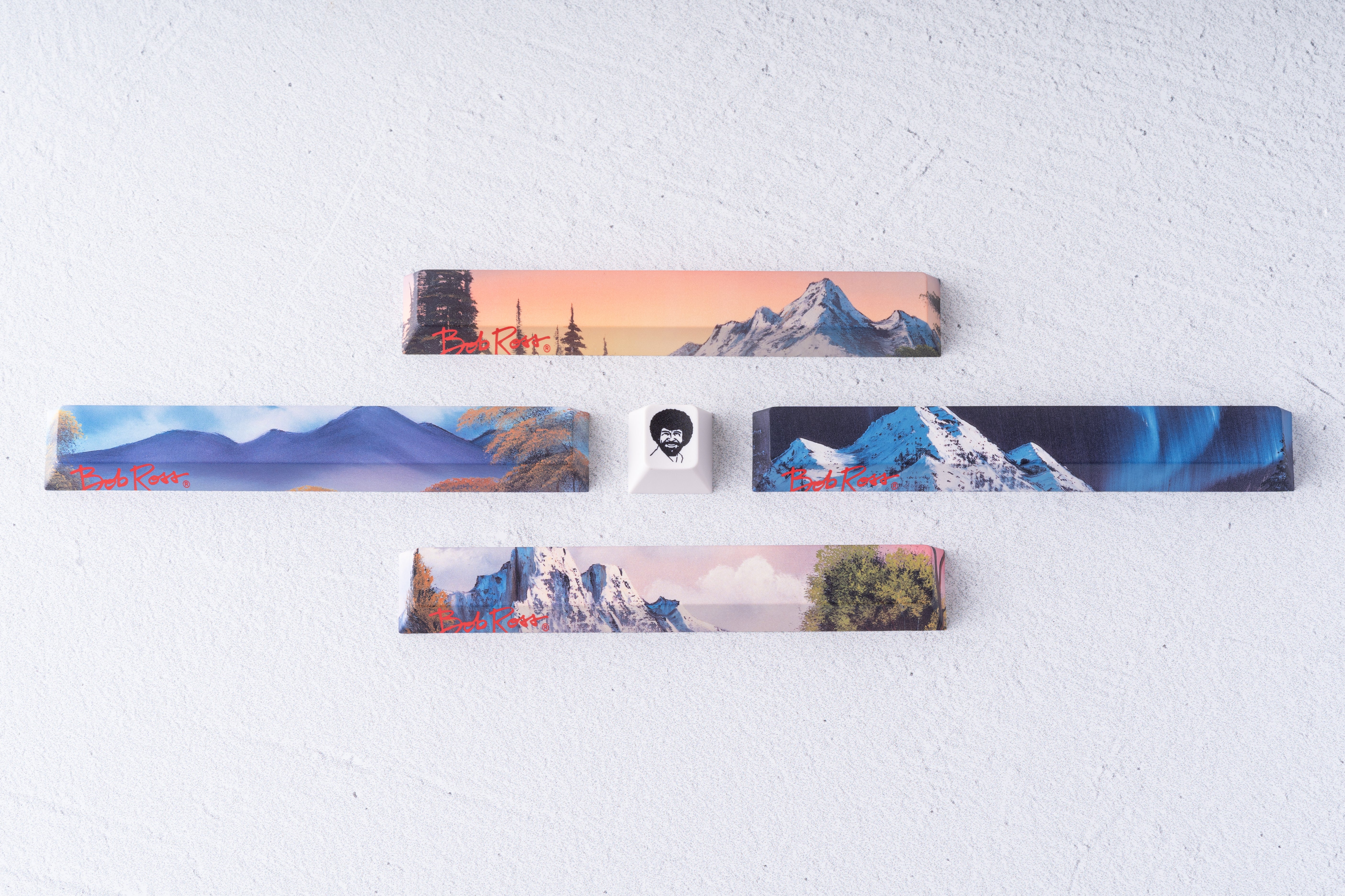 Apos x Bob Ross 키캡 4종 세트와 밥 로스 얼굴 ESC 키를 나란히 놓은 모습
