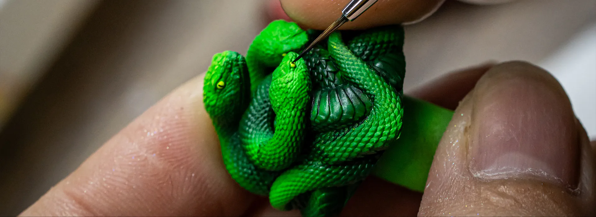 A craftsperson carefully hand-painting the snake's eye with a brush