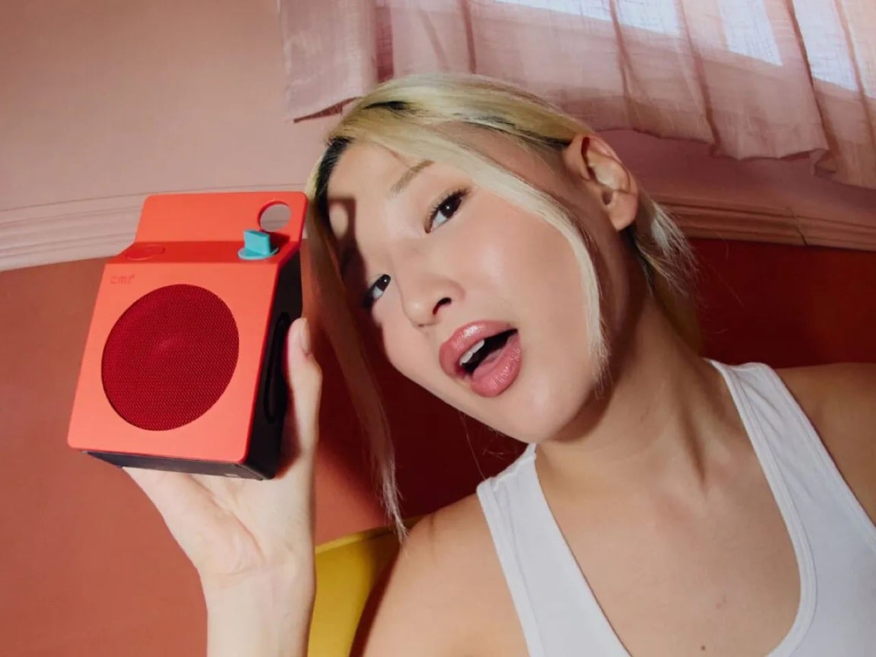 주황색 CMF 스피커를 들어 올린 모습